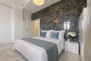 a bedroom with a large bed with a stone wall at White Loft by Symphonya Luxury Holiday Rentals in Gallipoli