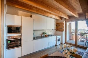 a kitchen with white cabinets and a large window at ANESI appartamenti in Baselga di Pinè