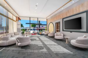 a lobby with white chairs and a flat screen tv at Arya inn suit in Serik