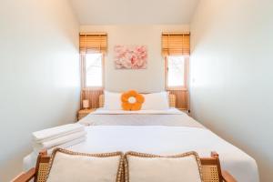 a bedroom with a large white bed with two windows at Nimman Bed at9 in Chiang Mai