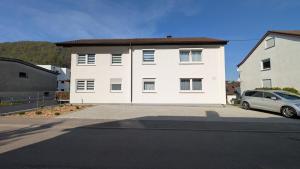 a white house with a car parked in front of it at Ferienwohnung Unterm Tierstein in Bad Ditzenbach