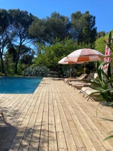 a wooden deck with two umbrellas and a swimming pool at La Finca in Nîmes