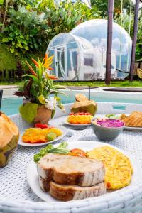 a table with bread and other foods on it at Bubble 9 - Luxury Private Pool Experience Ubud in Tampaksiring