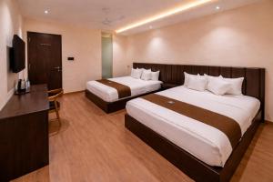 a hotel room with two beds and a television at Hotel Presidency - Sosyo Circle in Surat