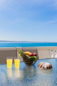 a table with a bowl of fruit and two glasses of orange juice at Apartman D&D in Starigrad