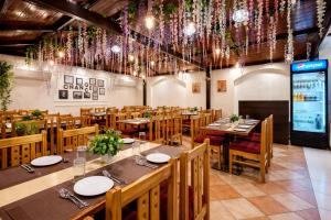a restaurant with wooden tables and chairs and chandeliers at Hotel Kant Palace in Tājganj