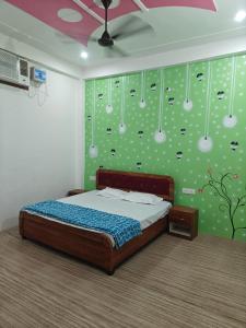 a bedroom with a bed and a green wall with pears at Shri Ram Vila Guest House in Ayodhya