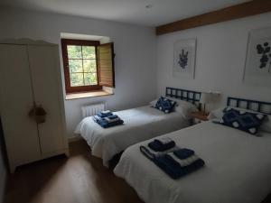 two beds in a bedroom with blue towels on them at Casa Eider in Rucandio