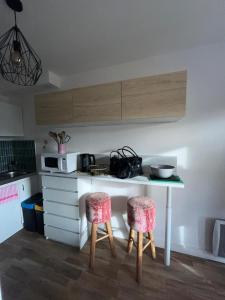 a kitchen with a table and two stools in a kitchen at Studio St Marc - plage à 300m in Saint-Nazaire