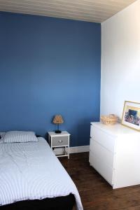 a blue bedroom with a bed and a dresser with a lamp at L'écoutille in Dieppe