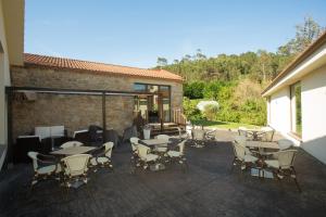 a patio with tables and chairs and a building at Hotel Alén do Mar in Finisterre