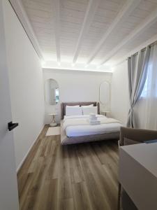 a white bedroom with a bed and wooden floors at The K Noir Private Pool Luxury Suite in Civé +5 photos