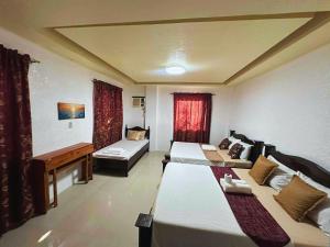 ein Hotelzimmer mit zwei Betten und einer Couch in der Unterkunft Cozy Stop Inn - Puerto Princesa in Puerto Princesa