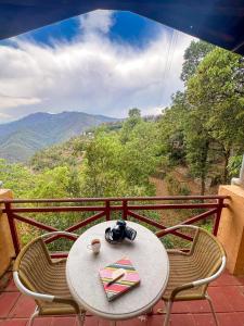 a table and chairs on a balcony with a view at Wild Meadows by Levitate - Exclusive Dual Bedroom Chalet Open Sky View & Fully Equipped Kitchen in Rāmgarh +35 photos