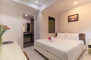 a bedroom with a white bed and a table at Sophia Central Nha Trang Hotel by HT in Nha Trang
