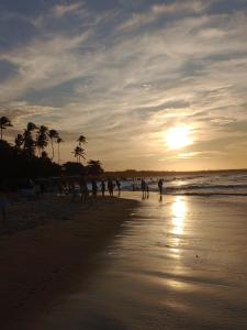 a group of people walking on the beach at sunset at Casa Carlotta in Paracuru