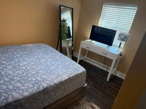 a bedroom with a bed and a desk and a television at Backyard Cottage in Naples