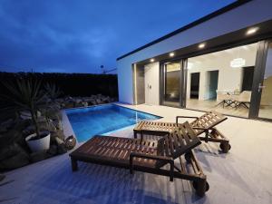 a house with a swimming pool and two benches at The K Noir Private Pool Luxury Suite in Civé