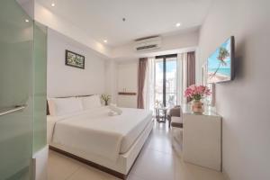 a white bedroom with a white bed and a window at Sophia Central Nha Trang Hotel by HT in Nha Trang