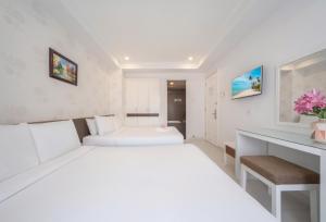 a white bedroom with two beds and a desk at Sophia Central Nha Trang Hotel by HT in Nha Trang