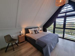 a bedroom with a bed and a large window at Lutz Watervilla's Balk in Balk