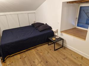 a bedroom with a bed and a table with a window at Maison en pierre Ardèche du sud in Valgorge