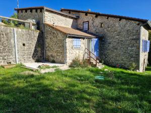 a stone house with a grassy yard in front of it at Maison en pierre Ardèche du sud in Valgorge