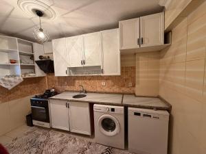a kitchen with white cabinets and a washing machine at Liva Konukevi in Ayvalık