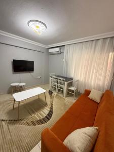 a living room with an orange couch and a table at Liva Konukevi in Ayvalık