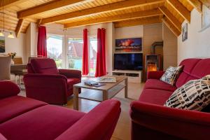 a living room with red couches and a tv at Ferienhaus Klapötke in Dorum