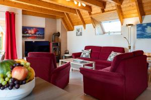 a living room with red couches and a table with fruit at Ferienhaus Klapötke in Dorum
