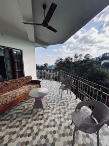 a patio with a couch and chairs on a balcony at The Hp 39 House in Dharmsāla
