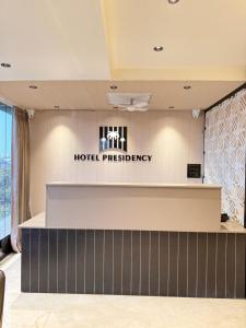 a hotel reception counter with a hotel presidency sign on the wall at Hotel Presidency - Sosyo Circle in Surat