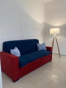 a red and blue couch in a room with a lamp at Trame - La Naca sul Porto in Polignano a Mare