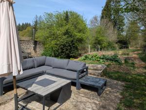 a couch and a table and an umbrella on a patio at Gîte romantique avec charme et confort in Soubrebost