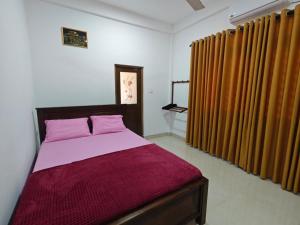 a bedroom with a bed with purple sheets and curtains at Galoya Red Lotus in Ampara
