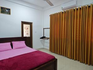 a bedroom with a bed and some curtains at Galoya Red Lotus in Ampara