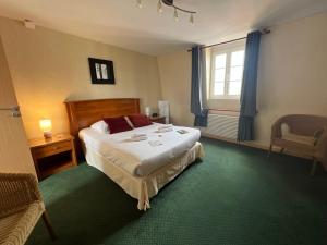 a bedroom with a bed and a chair and a window at Logis Hôtel Restaurant SPA Le Tosny in Épaignes