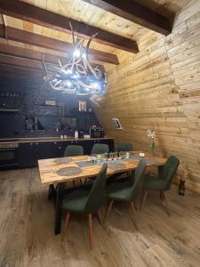 a dining room with a large wooden table and green chairs at Cabana A Vic in Taşca