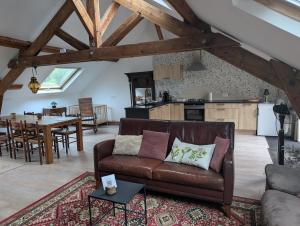 a living room with a brown couch and a kitchen at Gîte romantique avec charme et confort in Soubrebost
