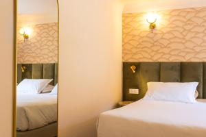 two beds in a hotel room with a mirror at Hôtel Restaurant Le Lachens in La Bastide