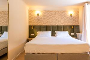 a bedroom with a large bed with white sheets at Hôtel Restaurant Le Lachens in La Bastide