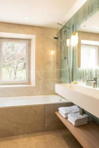 a bathroom with a tub and a sink and a window at Hôtel Restaurant Le Lachens in La Bastide