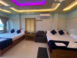 a hotel room with two beds and a chair at Hotel Raj in mayapur