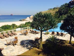 un complejo con sillas, piscina y playa en Camboinhas Oceanside Oceanfront, en Río de Janeiro