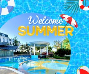 a swimming pool with an umbrella and a welcome summer sign at AMA Residences in Buon Ma Thuot