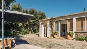 a house with an umbrella and a patio at Villa de la brune in Bormes-les-Mimosas