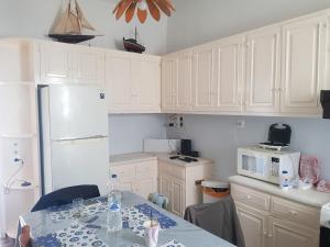 a kitchen with white cabinets and a table and a microwave at Nautilus andros house in Andros