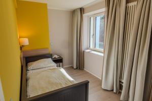 a bedroom with a bed with a yellow wall and a window at Lachmöwe B1-311 mit Meerblick und Balkon in Binz