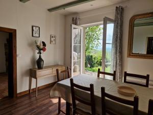 a dining room with a table and a large window at La maison Argonnaise in beaulieu en argonne